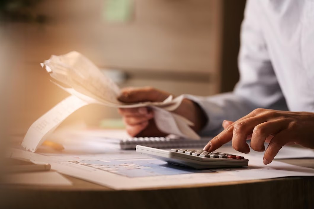 closeup-economist-using-calculator-while-going-through-bills-taxes-office_637285-3156 (1)